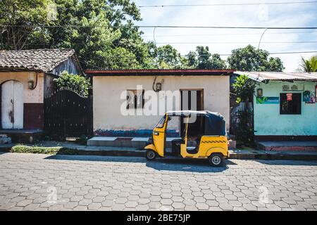 Le tuktuk jaune stationné à l'extérieur d'une petite maison à Pacaya, au Nicaragua Banque D'Images