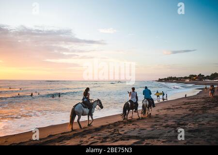 Vous pourrez faire de l'équitation à côté des surfeurs et des vacanciers qui se ranparmi les amateurs de randonnée sur la plage de Las Peñitas, sur la côte Pacifique du Nicaragua Banque D'Images