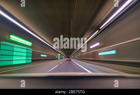 Voiture roulant rapidement en bas du tunnel intérieur, suivant une autre voiture. Banque D'Images