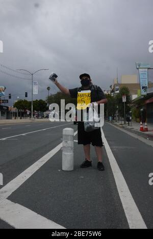 Les vendeurs de rue vendent de l'assainisseur à main et des masques le long du boulevard Venice. Banque D'Images