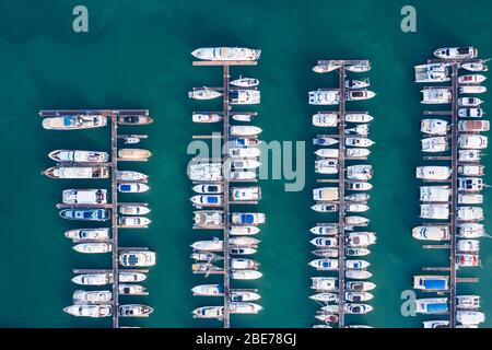 Vue aérienne d'un yacht à moteur blanc. Le yacht entre dans la baie dans le parking. De nombreux yachts différents, des catamarans amarrés aux piers. Yacht et tr chers Banque D'Images