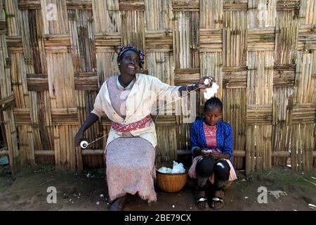 Dorze Tribe souriant femme assis devant une clôture en bambou démontrant la filature de la laine Banque D'Images