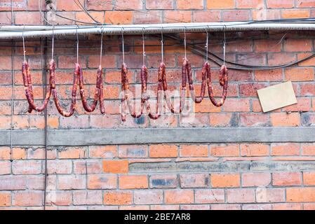 Saucisses accrochées sur un fil contre un mur de briques, Chengdu, province du Sichuan, Chine Banque D'Images