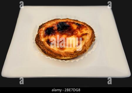 Pasteis de nata, dessert traditionnel de la crème anglaise portugaise, à base d'œufs, de cannelle, de sucre et de farine sur une plaque blanche à Porto, au Portugal Banque D'Images