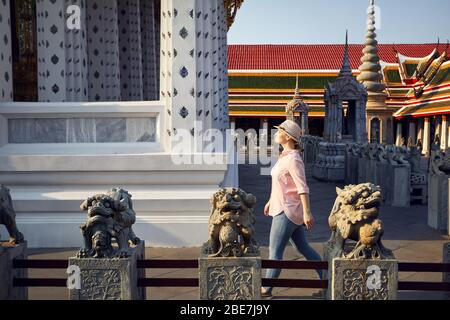 Bel'woman in hat et balades en chemise rose Wat Arun temple au coucher du soleil à Bangkok, Thaïlande Banque D'Images