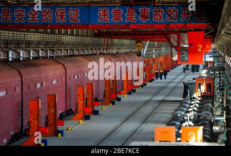 (200413) -- BEIJING, le 13 avril 2020 (Xinhua) -- un train frontalier chargé de véhicules entre dans l'atelier de remplacement des roues au port d'Erenhot dans la région autonome de la Mongolie intérieure nord, le 12 avril 2020. En raison de normes différentes de voie dans différents pays, les trains chargés de véhicules devaient faire face à un processus complexe de passage des frontières par le passé. La situation a changé maintenant. En utilisant le train spécialisé pour le transport de véhicules avec des bogie et des dispositifs de coupleur amovibles, les trains chargés de véhicules peuvent passer par le port Erenhot sans décharge et r Banque D'Images