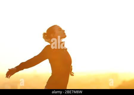Profil d'un coureur qui respire profondément l'air frais qui dépasse les bras au coucher du soleil
