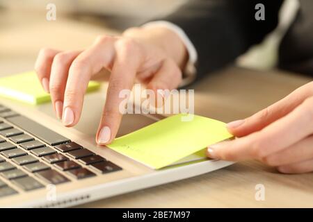 Gros plan sur les mains d'une femme de direction qui colle la note post sur un ordinateur portable assis sur un bureau Banque D'Images