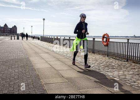 Jogger longeant le front de mer de Mersey sur Kings Parade, Liverpool Banque D'Images