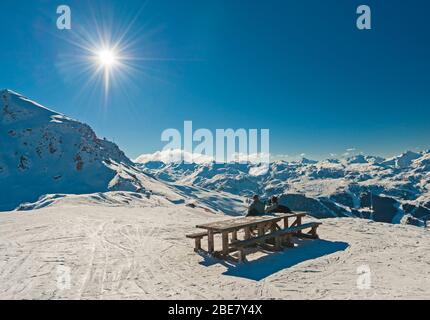 Vue panoramique sur la chaîne de montagnes alpine avec deux skieurs assis à la table de pique-nique se détendre sur la piste Banque D'Images