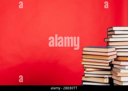 de nombreuses piles de livres éducatifs à étudier dans la bibliothèque de l'université sur un fond rouge Banque D'Images