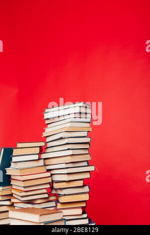 de nombreuses piles de livres éducatifs à étudier dans la bibliothèque de l'université sur un fond rouge Banque D'Images