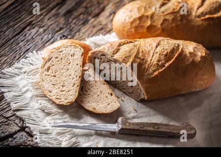 Deux tranches de pain cuit croustillant sur un tissu rustique et fond en bois avec un couteau sur le côté. Banque D'Images