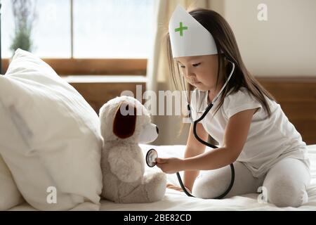 Le phonendoscope de petite fille asiatique écoute les battements de cœur à un jouet farci Banque D'Images