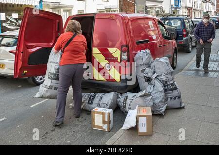 Une employée de la poste a occupé à recueillir de lourds sacs de courrier du bureau de poste de Presteigne, au Pays de Galles, au Royaume-Uni, pendant la pandémie de coronavirus Banque D'Images