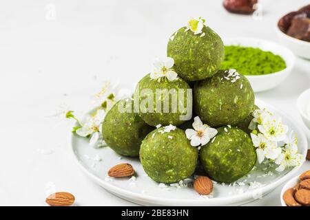 Boulettes d'énergie de matcha vert ou morsures d'énergie faites de dates et de noix avec des fleurs de printemps. En-cas diététiques végétaliens. Style des aliments. Gros plan avec copie de l'épic Banque D'Images