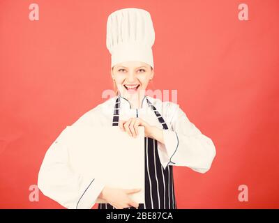 Femme au foyer avec livre de cuisine. happy woman cooking alimentation saine par recette. chef professionnel en cuisine. Cuisine. menu du restaurant. Suivre un régime culinaire. femme dans cook hat et tablier. Look sympathique. Banque D'Images