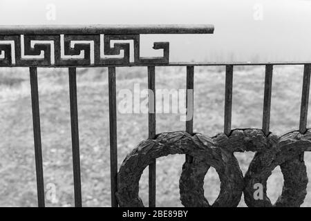 Vieille rampe en fonte cassée avec un motif classique, fragment extérieur abandonné du bâtiment. Photo en noir et blanc Banque D'Images