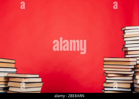 de nombreuses piles de livres éducatifs à étudier dans la bibliothèque de l'université sur un fond rouge Banque D'Images