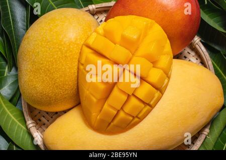Mangue, fruits tropicaux, dans un panier en bois de bambou sur fond de feuilles vertes, vue de dessus, plein cadre, beau, mûre conception de récolte concept. Banque D'Images