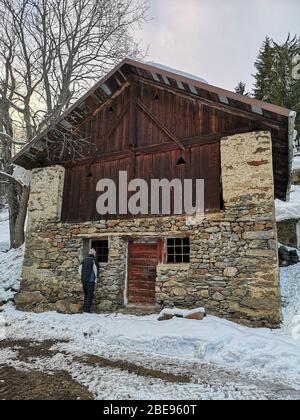 Ancienne grange en pierre et planches en bois entourées de neige dans un style typique alpin lors d'une journée froide d'hiver Banque D'Images