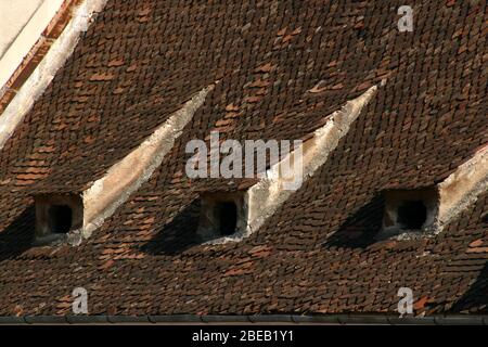 Ouvertures à travers le toit d'origine en tuiles de maisons historiques dans la vieille ville de Brasov, Roumanie Banque D'Images