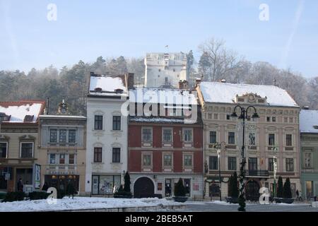 Vieux bâtiments adjacents autour de la place du Hall de Brasov, Roumanie, avec la tour de surveillance blanche vue à l'arrière Banque D'Images