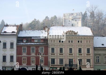 Vieux bâtiments adjacents autour de la place du Hall de Brasov, Roumanie, avec la tour de surveillance blanche vue à l'arrière. Le palais Safrano (le plus grand). Banque D'Images