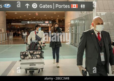 Les gens traversent l'aéroport international Pearson de Toronto, le 16 mars 2020. Dans un contexte de mesures de sécurité visant à ralentir la propagation du virus COVID-19, le premier ministre du Canada, Justin Trudeau, a limité les déplacements au Canada, en provenance de nombreux pays internationaux. Pearson sera l'un des aéroports désignés au Canada qui sera autorisé à accepter des vols internationaux limités. Banque D'Images