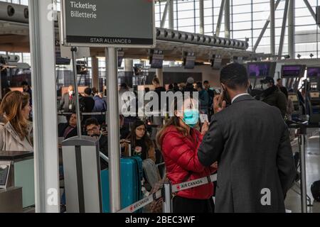 Les gens attendent de parler à des représentants au comptoir de billetterie d'Air Canada à l'aéroport international Pearson de Toronto, le 16 mars 2020. Dans un contexte de mesures de sécurité visant à ralentir la propagation du virus COVID-19, le premier ministre du Canada, Justin Trudeau, a limité les déplacements au Canada, en provenance de nombreux pays internationaux. Pearson sera l'un des aéroports désignés au Canada qui sera autorisé à accepter des vols internationaux limités. Banque D'Images