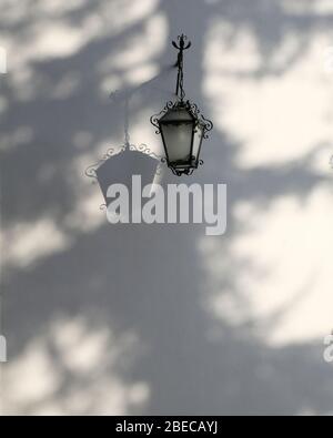 Un beau mur blanc jeté dans les ombres d'un arbre avec une applique murale traditionnelle. Banque D'Images