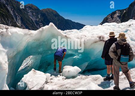 Les touristes en regardant d'un guide examine une grotte de glace bleue sur le Franz Joseph Glacier, François-Joseph, île du Sud, Nouvelle-Zélande. Banque D'Images