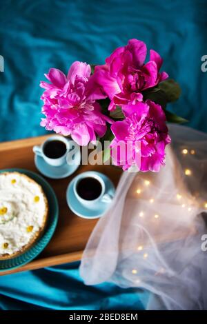 Beau matin cheesecake vanille, café, tasses bleu, rose de pivoines dans un vase en verre Banque D'Images