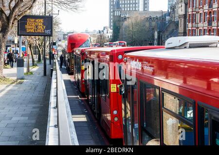 Un panneau matriciel indiquant « tay home, Essential Travel only, SAVE Lives » à côté d'un stand de bus vides pendant le verrouillage du coronavirus, Londres, Royaume-Uni Banque D'Images