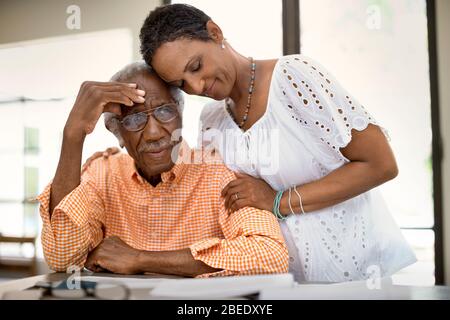 Femme adulte moyenne réconfortant son père senior tout en se rendant sur les finances personnelles Banque D'Images