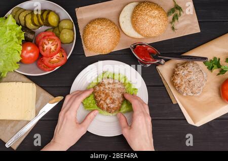 Cuisiner un hamburger maison étape par étape. Étape 5. Poser les viandes sur la salade sur le pain avec des sauces. Plat. Pour la publicité. Banque D'Images