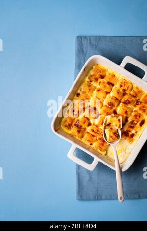 Gnocchi maison avec sauce au fromage dans un plateau de four sur la table bleue. Plat avec gnocchi au fromage frais. Cuisine italienne traditionnelle. Banque D'Images