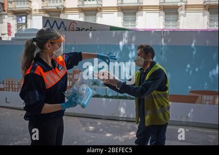 Un membre de la protection civile espagnole donne un masque facial à un citoyen comme mesure préventive contre la propagation de Covid-19 pendant un verrouillage. Des milliers d'Espagnols reprennent leur emploi après avoir terminé l'arrêt de toutes les activités et services de travail non essentiels et de revenir à l'état d'alarme original et de verrouillage depuis le début de l'éclosion de coronavirus (COVID-19) en Espagne. Tous les gens sont fermés dans leur maison après le confinement décrété par le gouvernement espagnol et qui sera prolongé jusqu'au 10 mai. Banque D'Images