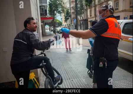 Un membre de la protection civile espagnole donne un masque facial à un citoyen comme mesure préventive contre la propagation de Covid-19 pendant un verrouillage. Des milliers d'Espagnols reprennent leur emploi après avoir terminé l'arrêt de toutes les activités et services de travail non essentiels et de revenir à l'état d'alarme original et de verrouillage depuis le début de l'éclosion de coronavirus (COVID-19) en Espagne. Tous les gens sont fermés dans leur maison après le confinement décrété par le gouvernement espagnol et qui sera prolongé jusqu'au 10 mai. Banque D'Images