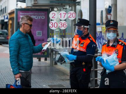 Un membre de la protection civile espagnole donne un masque facial à un citoyen comme mesure préventive contre la propagation de Covid-19 pendant un verrouillage. Des milliers d'Espagnols reprennent leur emploi après avoir terminé l'arrêt de toutes les activités et services de travail non essentiels et de revenir à l'état d'alarme original et de verrouillage depuis le début de l'éclosion de coronavirus (COVID-19) en Espagne. Tous les gens sont fermés dans leur maison après le confinement décrété par le gouvernement espagnol et qui sera prolongé jusqu'au 10 mai. Banque D'Images