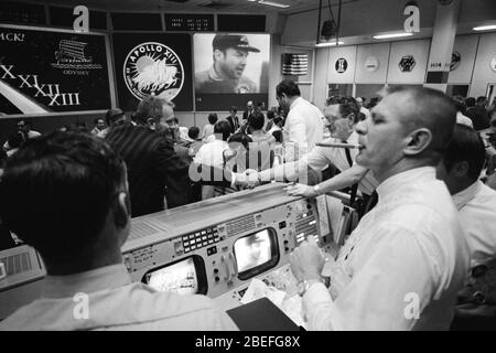 Deke Slayton (dans le maillot noir, à gauche du centre) directeur des opérations d'équipage de conduite et Chester M. Lee se serrent les mains dans Mission Control, tandis que Rocco Petrone montre Jim Lovell, commandant de l'Apollo 13 à l'écran. Apollo 13, lancé le 11 avril 1970, était la troisième mission créée de la NASA sur la lune. Deux jours plus tard, le 13 avril, alors qu'en route vers la surface lunaire, une défaillance du système électrique de l'un des réservoirs d'oxygène du module de service a provoqué une explosion qui a causé la défaillance des deux réservoirs d'oxygène et a également entraîné une perte d'alimentation électrique. La mission étant abandonnée, une équipe dédiée dans l'Apollo MI Banque D'Images