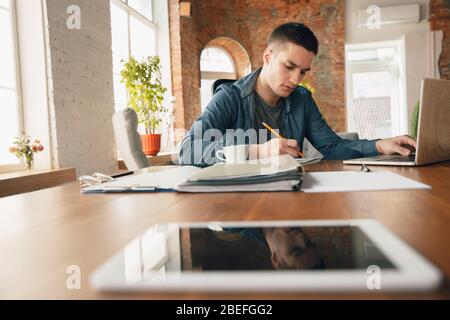 Espace de travail créatif - espace de travail organisé comme vous le souhaitez pour vous inspirer. Homme travaillant au bureau dans une tenue confortable, une position détendue et une table désordonnée. Choisissez l'atmosphère que vous voulez - idéal clair ou chaos. Banque D'Images