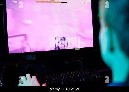 Vue arrière du joueur assis devant l'écran d'ordinateur et jouant au jeu vidéo dans le club d'ordinateur Banque D'Images