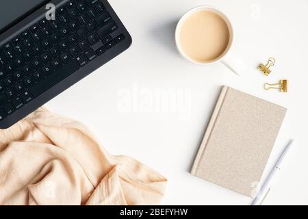 Bureau confortable avec ordinateur portable, tasse de café, carnet en papier, plat. Vue du dessus élégant espace de travail féminin. Travailler à domicile Banque D'Images
