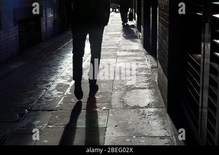 Silhouette d'un homme dans le contre-jour marchant dans la rue au soleil couchant. Banque D'Images