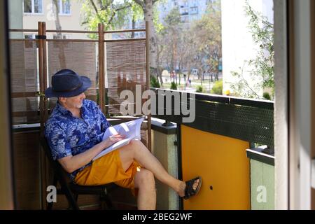 homme sur le balcon de sa maison, un gars dans un chapeau, le gars lit un livre sur le balcon Banque D'Images