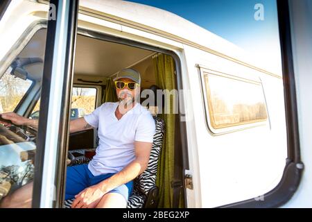 Portrait de l'homme avec lunettes de soleil pendant les vacances dans sa camionnette Banque D'Images