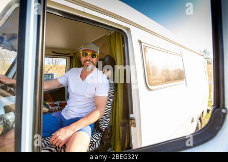 Portrait de l'homme avec lunettes de soleil pendant les vacances dans sa camionnette Banque D'Images