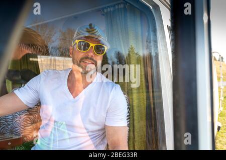 Portrait de l'homme avec lunettes de soleil pendant les vacances dans sa camionnette Banque D'Images