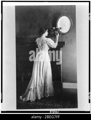 Helen Keller, portrait en pied, faisant face à droite, debout à cheminée avec des fleurs sur le manteau Banque D'Images